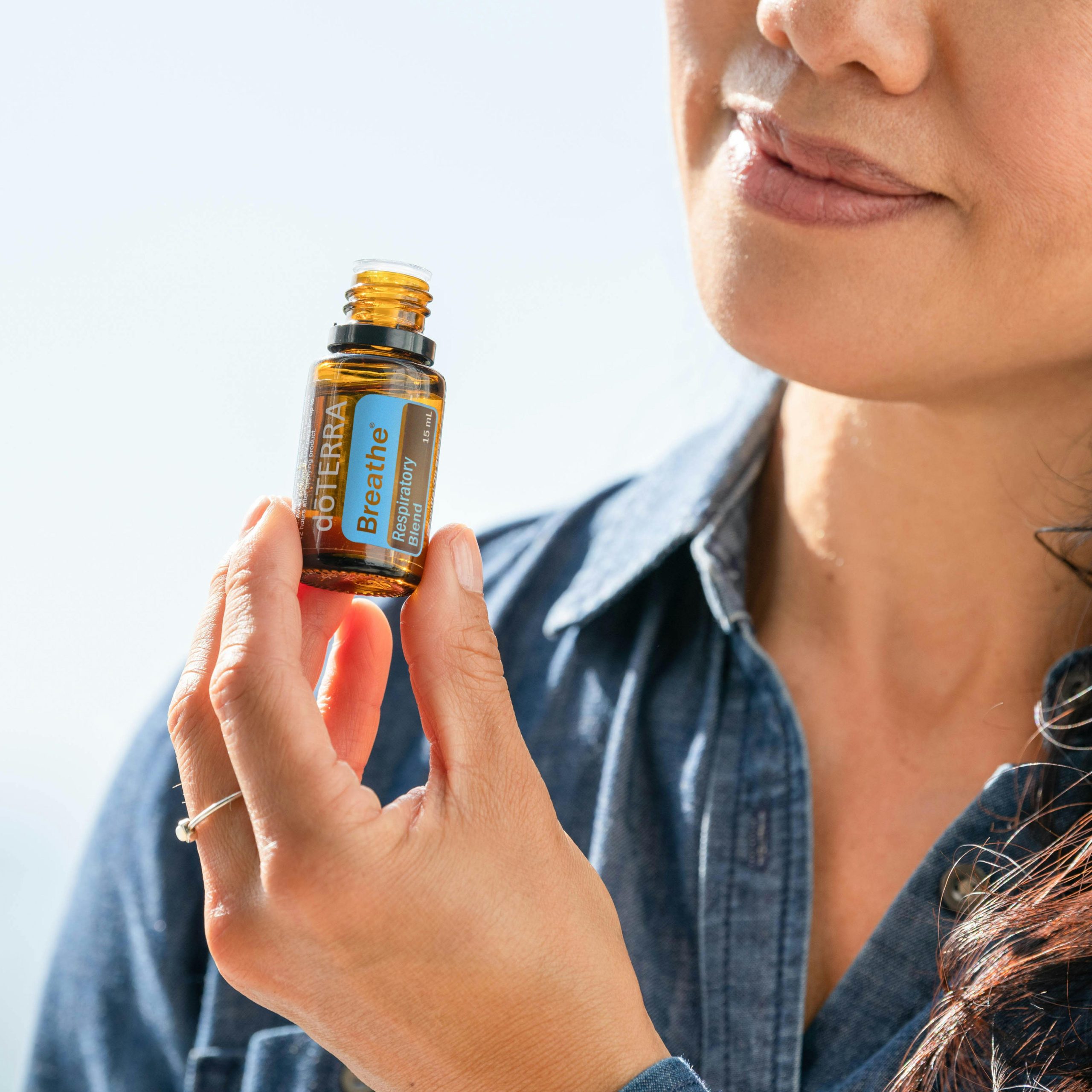 Close-up image of a woman holding an essential oil bottle in natural lighting.