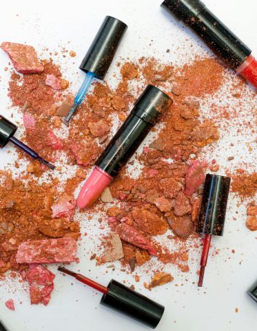 pexels-photo-1377034-1377034 Colorful scattered makeup products including lipsticks and crushed powders on a white background.