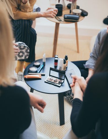 pexels-photo-1884582-1884582 Women gathered around a table applying cosmetics, fostering a collaborative workspace.