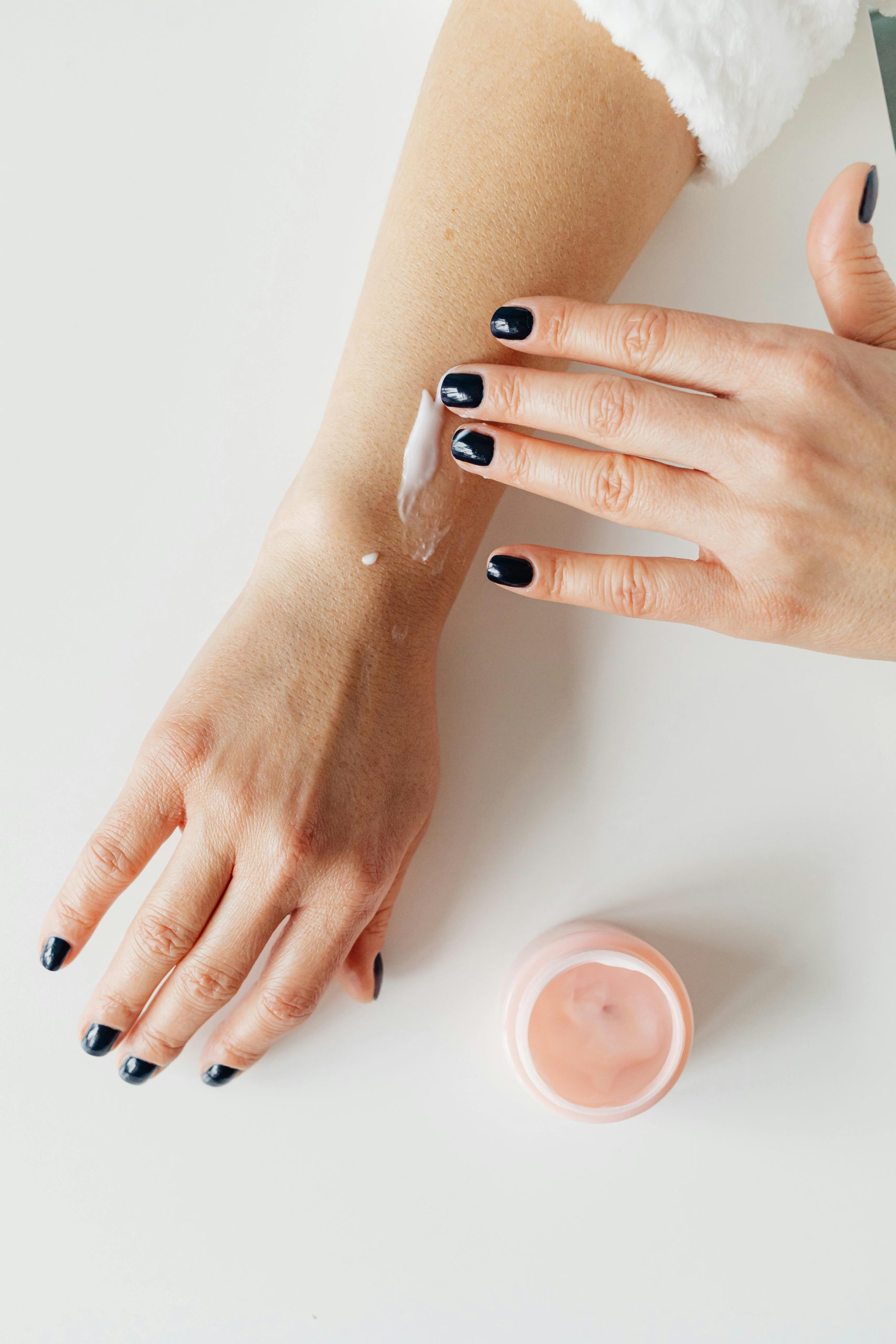 A close-up image of hands applying skincare cream on an arm, conveying beauty and self-care.
